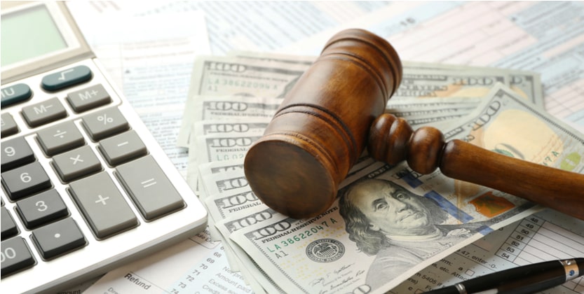 gavel calculator and hundred dollar bills representing a lawsuit settlement