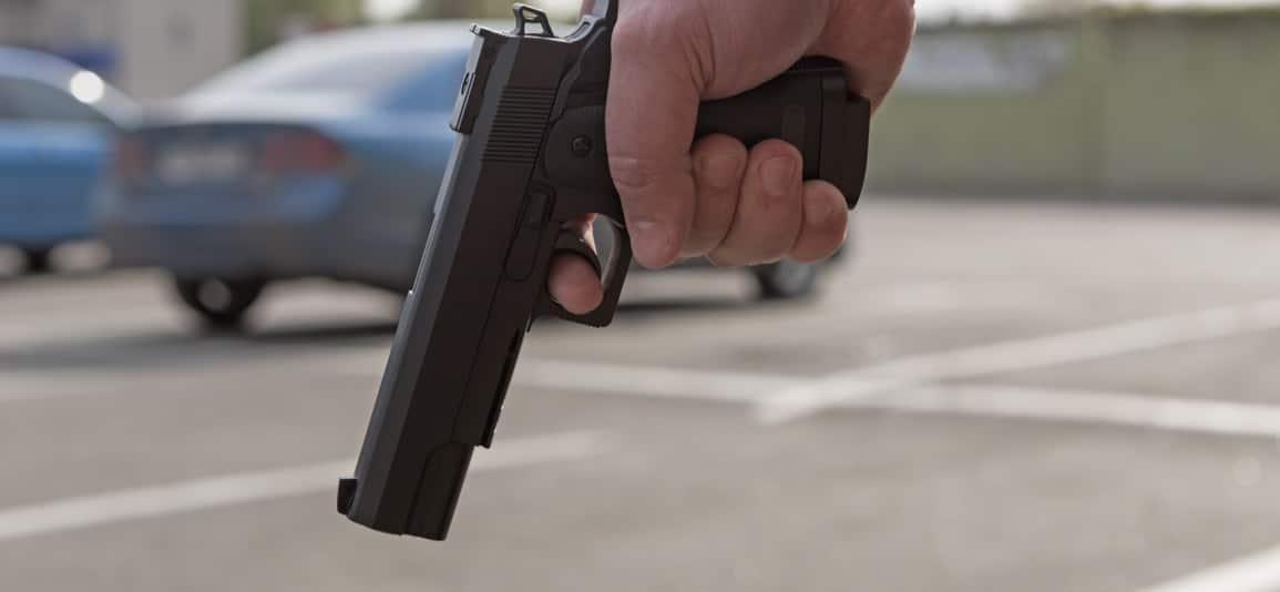 man holding a firearm before being arrested for weapons charge