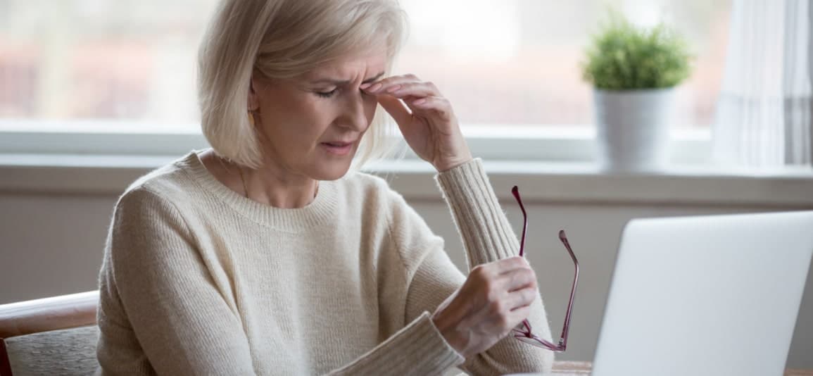 Older woman with hand on head suffering from vision loss